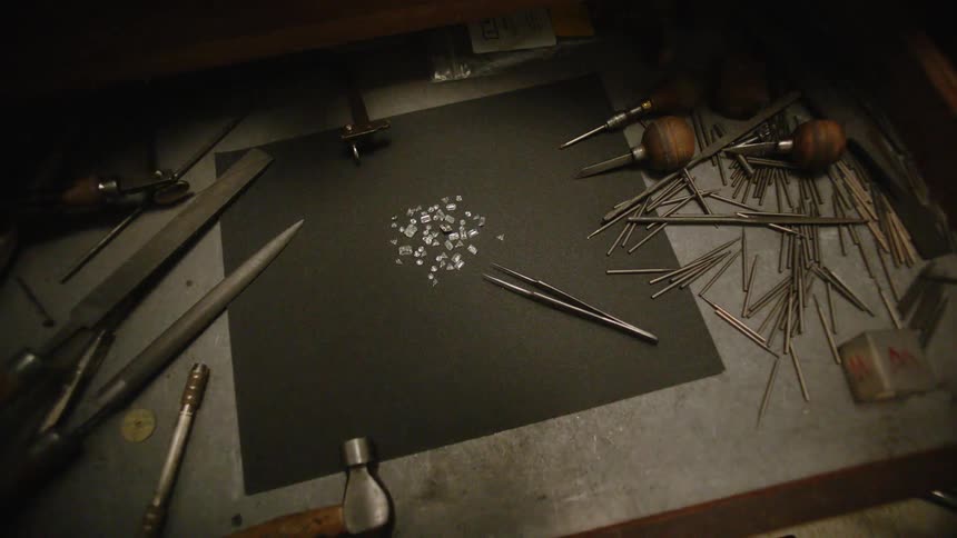 Pile of jewels on a desk next to tweezers