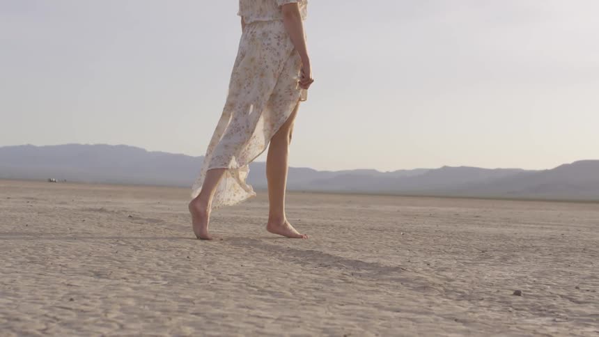 A woman that is walking around on a dry lake bed