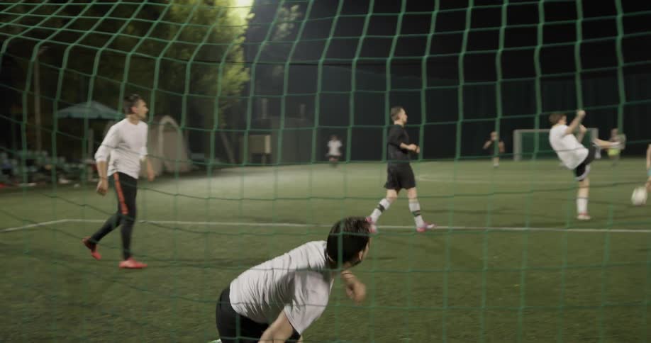 Two teams of boys play soccer on a field and the goalie of one team blocks two goals from being made