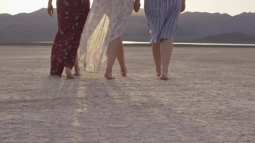 Three people walking across the dry dirt