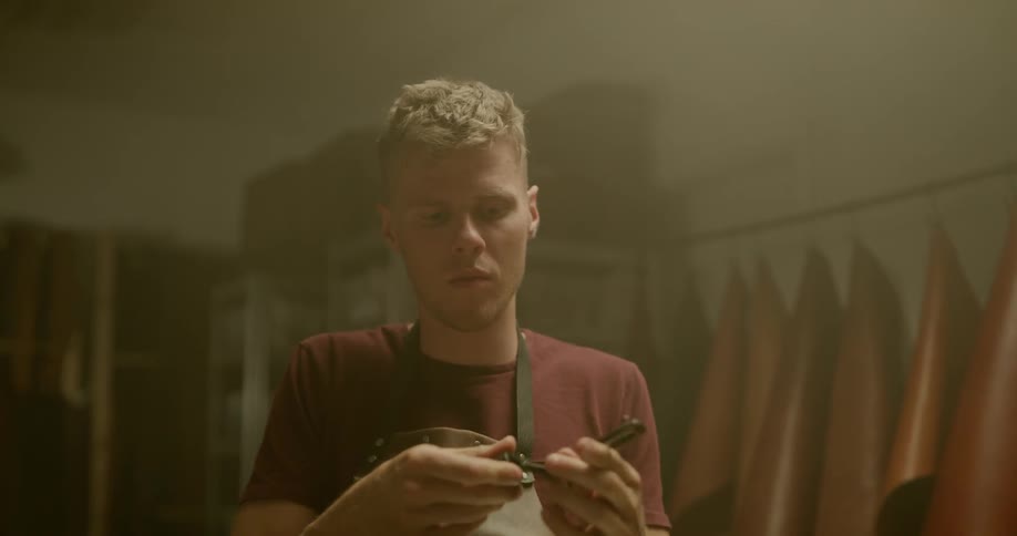 Man wearing an apron repairing a leather belt