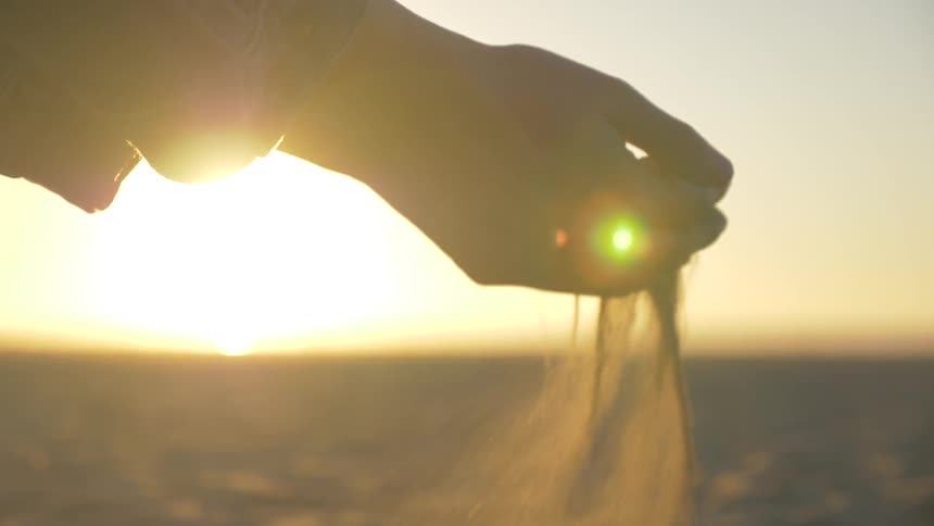 Person holds sand as it flows through his or her fingers