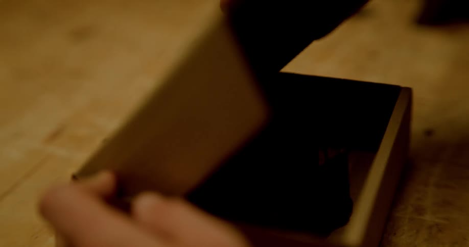 Man places rolled leather belt in cardboard box