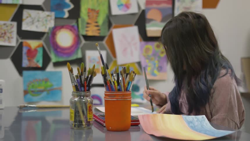 A young child uses a paint brush