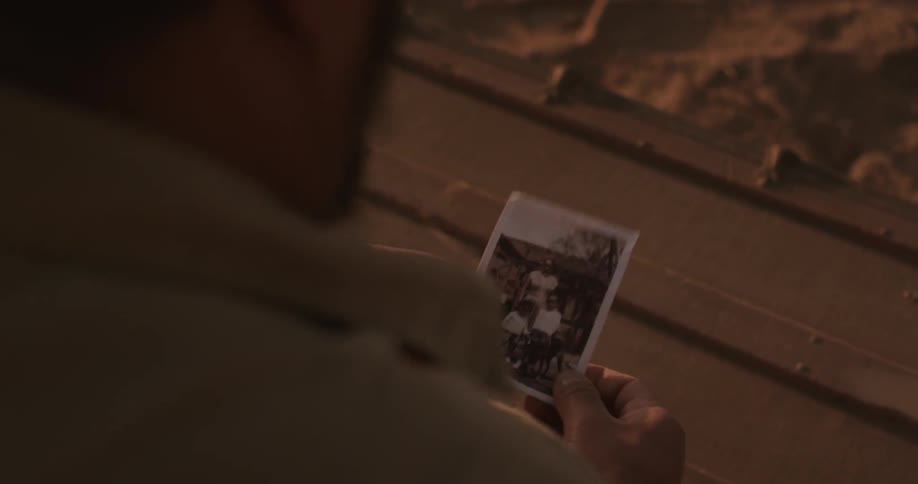 Person holds a picture and looks at it then puts it in his shirt pocket