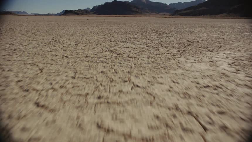 Cracked soil covers a field near mountains