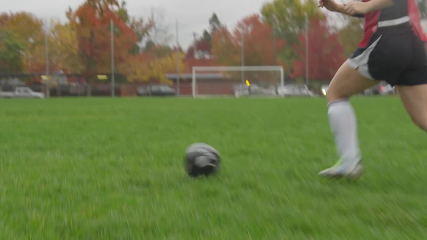 Two people sprint and kick soccer ball back and forth