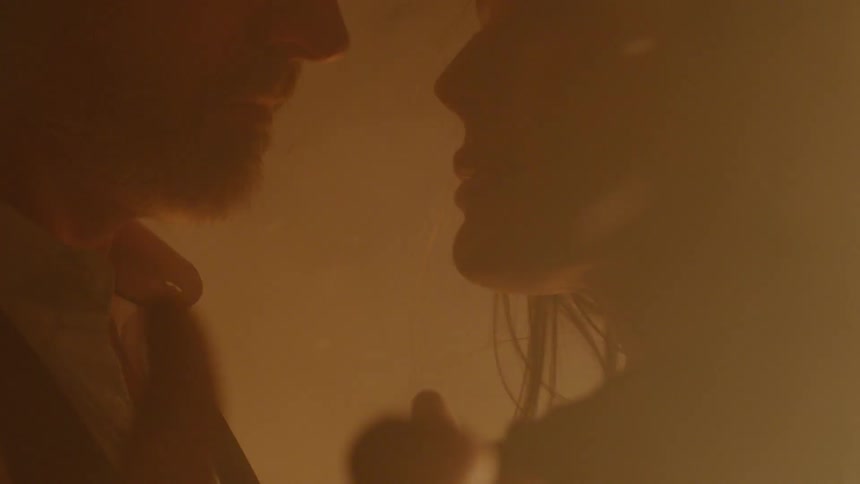 A man and a woman hug as smoke and ash fly by them