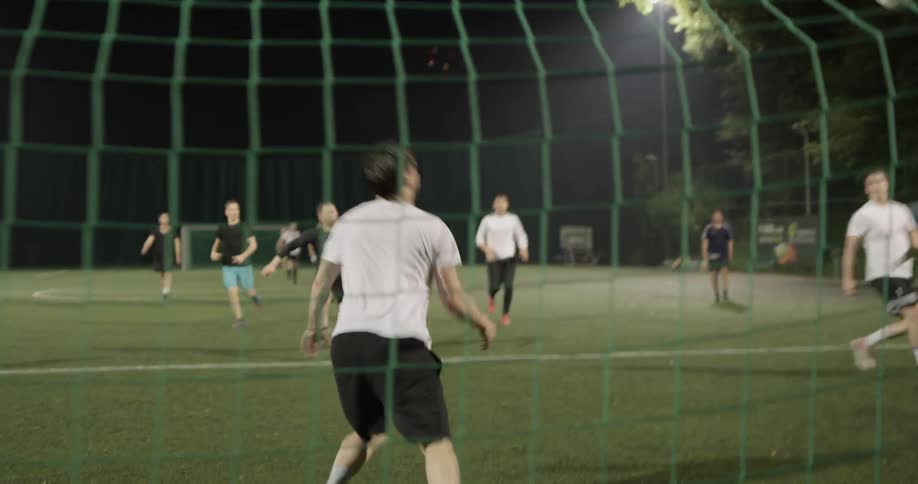 A group of people playing soccer at night