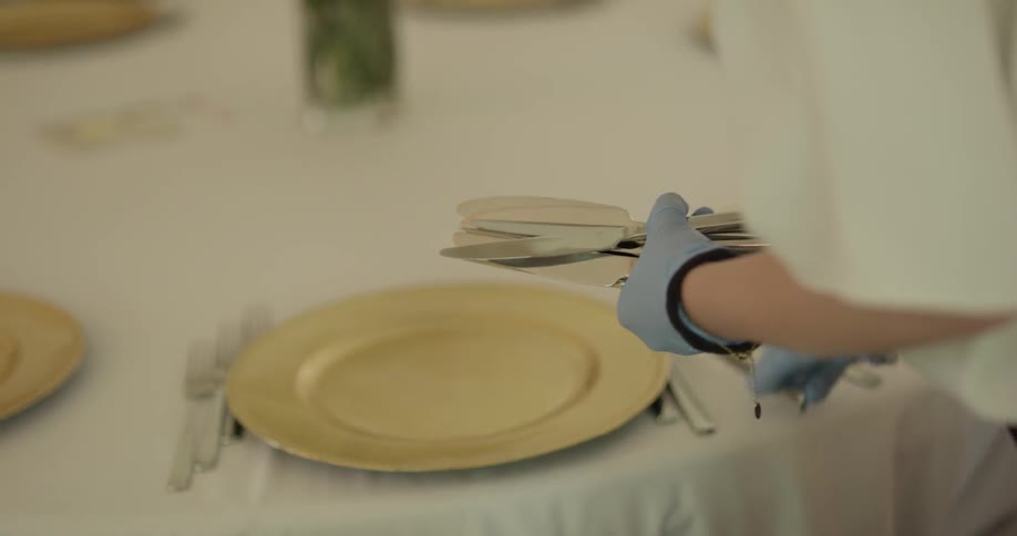 A person setting silverware on a table