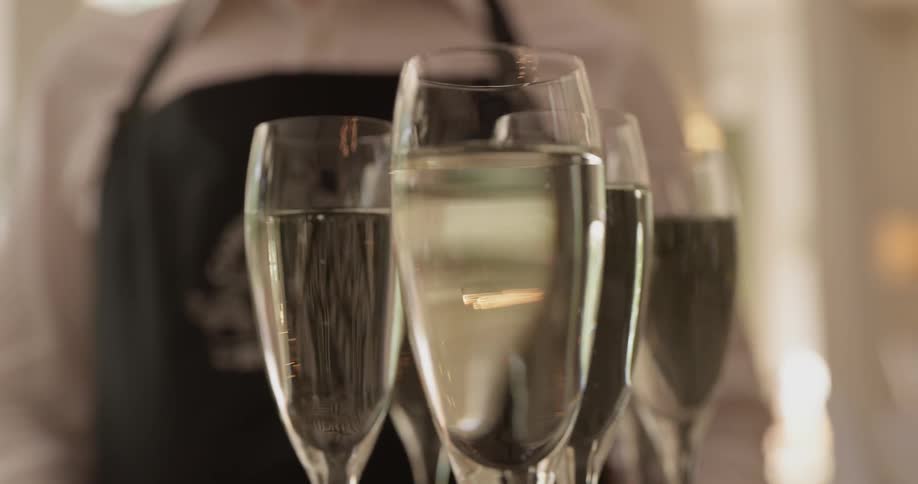 A waiter holds a tray of bubbling champagne