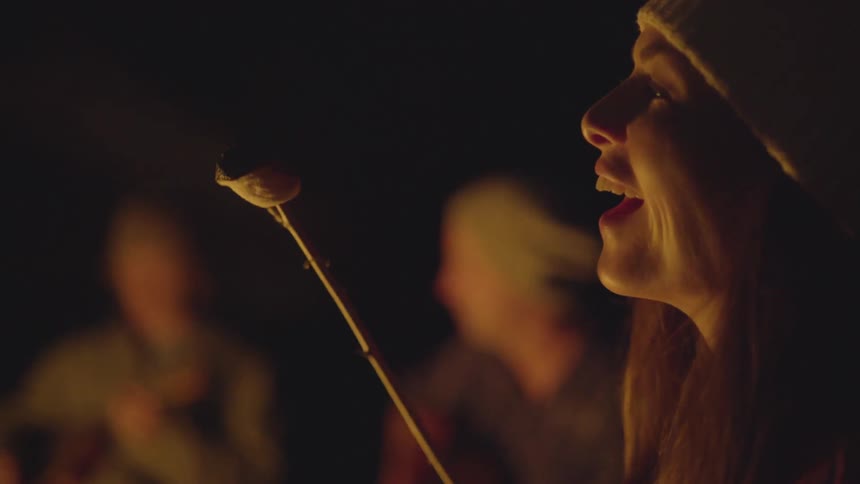 A woman blows out the flame from a marshmallow