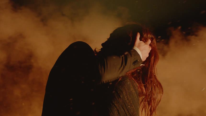 Man and woman holding each other in a plume of smoke