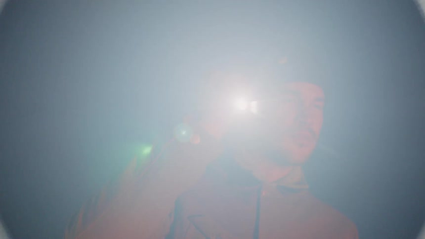 Man carries a flashlight next to his face in the dark