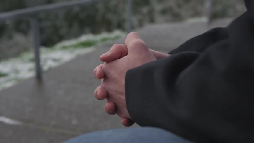A man holding his hands while sitting