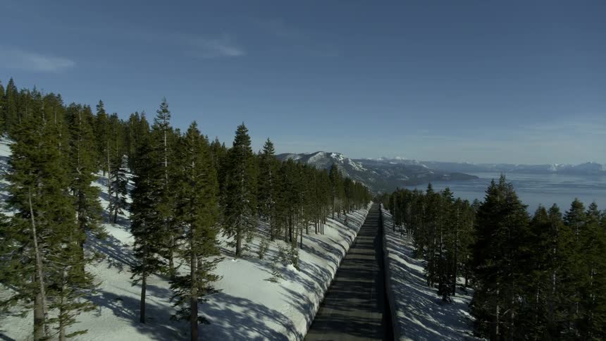Snow lined forest with mountains and pine trees and a 2 lane road