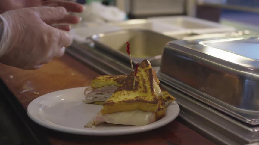A restaurant worker plates a sandwich