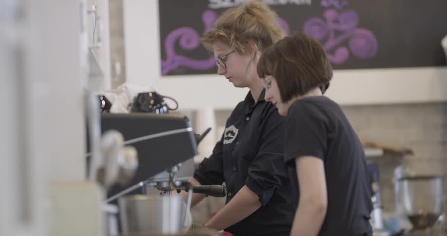 Two women making coffee in a cafe