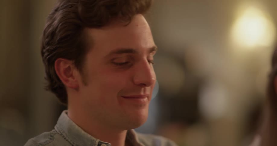 Man smiles while seated and talking with others