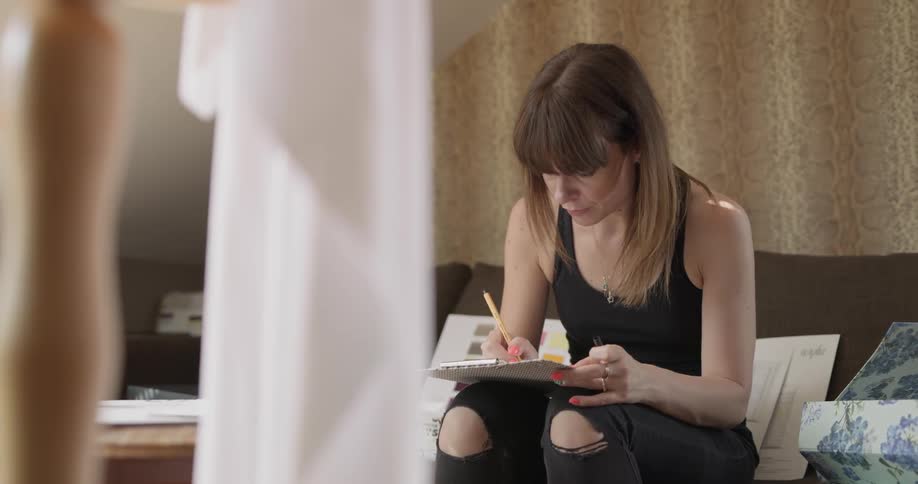 A woman is drawing while sitting on the couch