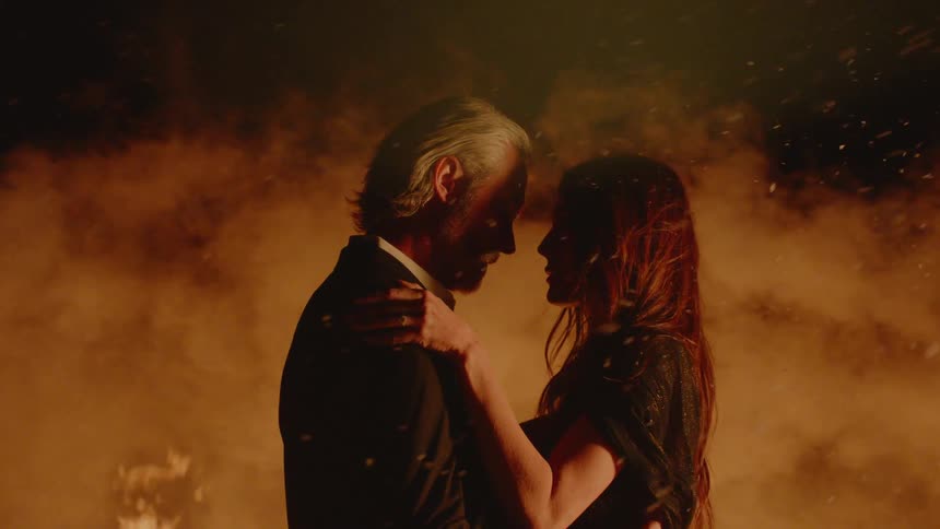 A man and woman hugging in front of a fire