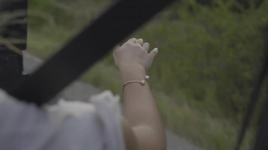 A woman waves her hand out an open car window