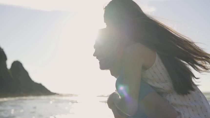 A woman riding a guy's back at the ocean