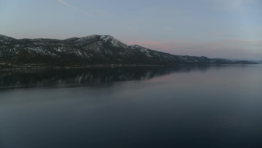 Sun sets over hills and a large body of water
