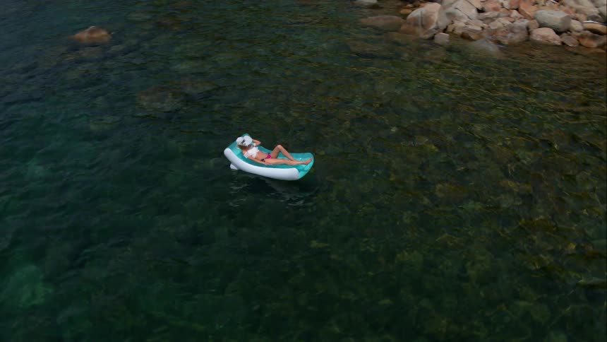 Woman Sunbathing On Raft In Water