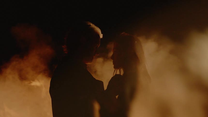 A man is kissing a woman by a fire