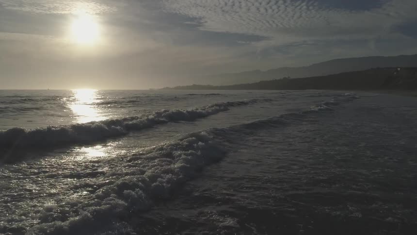 The sun sets as waves gently roll onto the shore