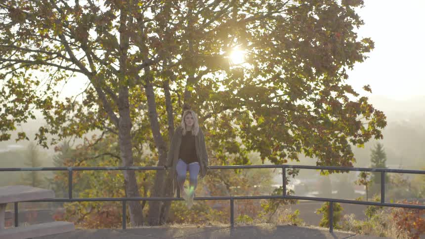 A woman is sitting on a ledge outside