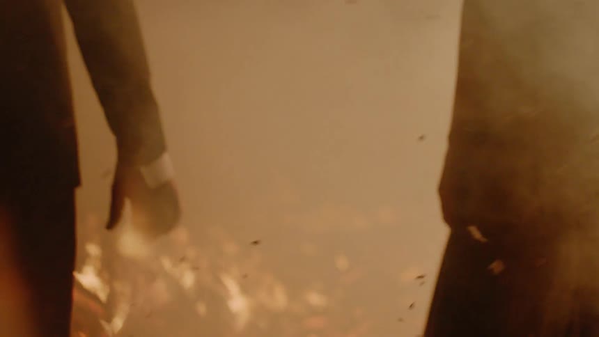 A woman and man are holding hands by a fire