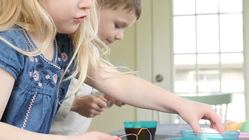 Children are coloring easter eggs at the table