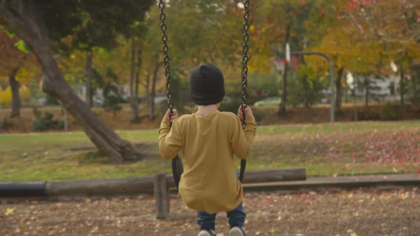 A young boy swings on the swing set