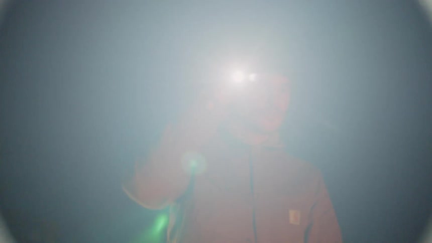 A man walking in a field with a flashlight