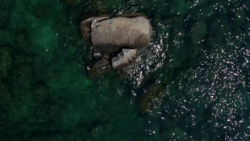 A rock is surrounded by rippling water