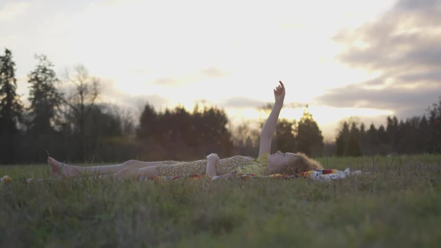 A girl laying on a blanket out in a field