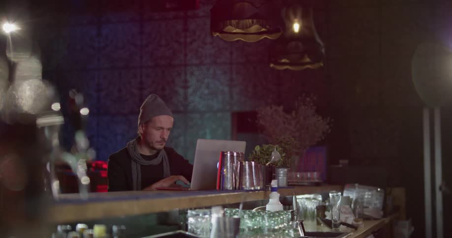 Man works on laptop at restaurant bar