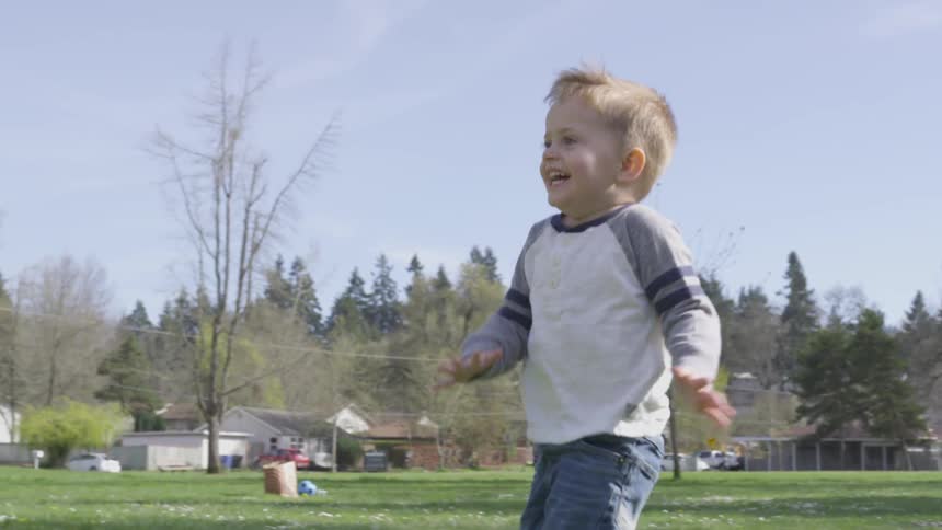 A young boy running and playing with bubbles