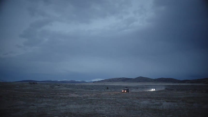 Two cars are driving in a rural area