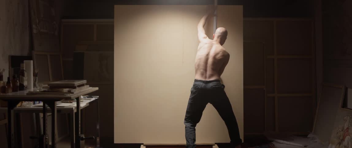 Man measures a large canvas with a ruler and draws a line