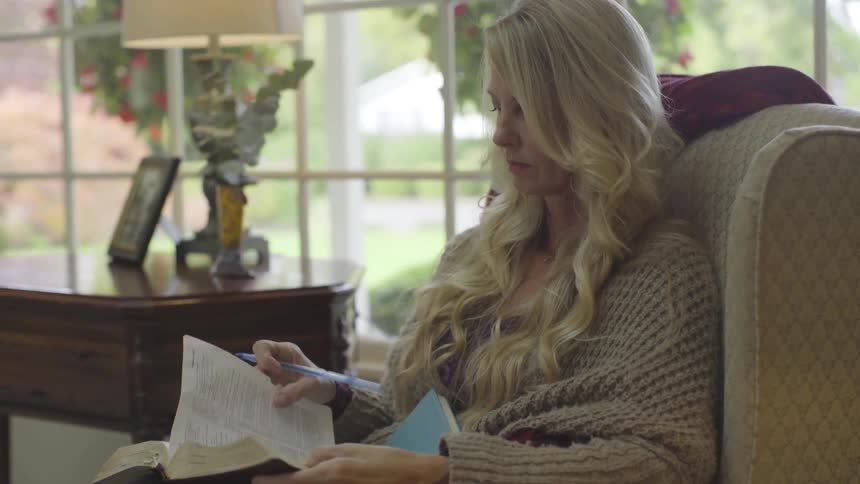 A woman sitting in a living room reading a book
