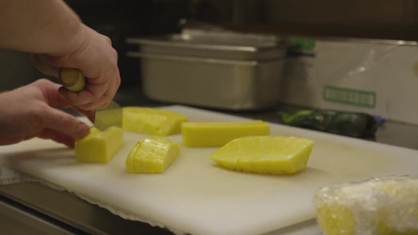A person is cutting pineapples on a table