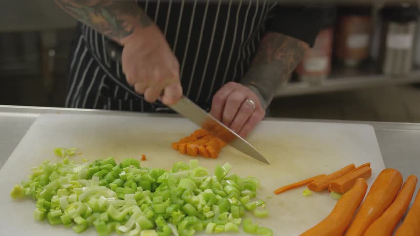 A man chops carrots on a cutting board