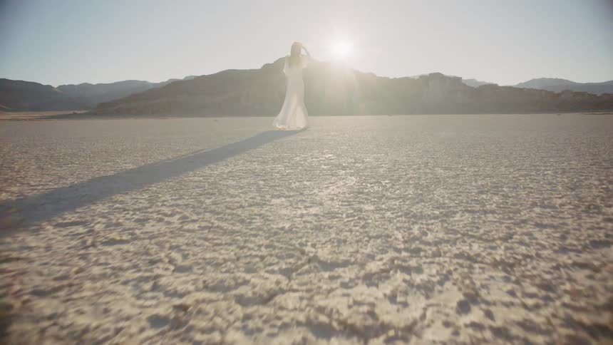 A woman standing in the desert looking at the sun
