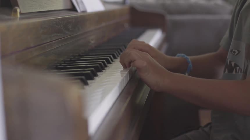 Child with bracelet on right hand plays piano