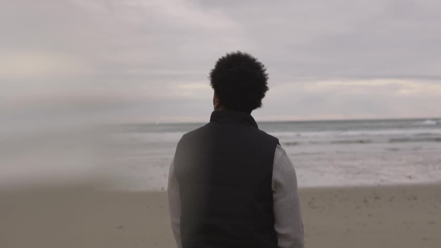 Man looking around a cloudy beach