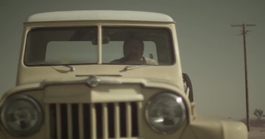 Man driving an older tan truck