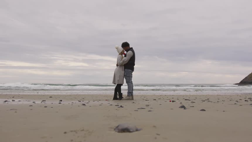 A couple is holding each other on the beach